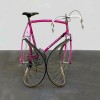 un vélo de course rose plié de façon à ce que le pneu de la roue arrière touche celui de la roue avant