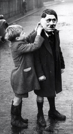 Adjusting_Adolf_Hitler_mask_on_a_street_in_King_s_Cross_London_1938.jpg