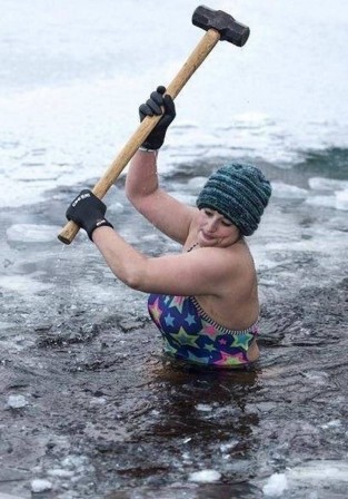 Euan Cherry Alice Goodridge using a sledgehammer to break up the ice at Loch Insh in the Scottish Highlands before her morning swim.jpg, nov. 2019