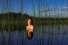 les épaules et la tête d'une femme émergent d'un plan d'eau avec roseaux et leur reflet donnent l'impression d'une figure de dame de jeu de carte, femme tronc au petit corps doublé