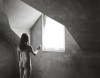 une femme nue, la main tendue vers une fenêtre d'où émane une vive lumière
