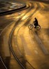 dans une lumière dorée sur la ville, un cycliste près d'une place où sa route croise la voie sinueuse du tramway