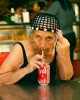 une vieille femme sirotant  à la paille une canette de Coca-Cola fait un doigt d'honneur au photographe