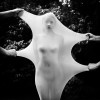 dans un jardin, des mains d'hommes tirent sur le voile intégral couvrant une femme nue