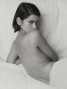 Aris Jerome femme nue appuyée sur son coude dans son lit regardant le photographe