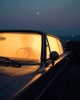 une silhouette au volant d'une voiture stationnée dans la nuit, puissamment éclairée de l'intérieur