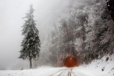 l'entrée orange du tunnel ferroviaire dans la montagne sous la neige et la brume