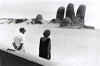 un couple face à une main géante émergeant du sable
