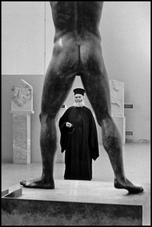 Elliott Erwitt Greece. 1963 Musée de l'Acropole Athènes prêtre orthodoxe et statue antique en bronze quand l'homme écarte les jambes on voit dieu