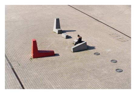 sur une place publique trois sculptures une femme assise au sommet du triangle