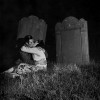 dans un cimetière, assis sur une tombe, deux amoureux s'embrassent