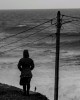 au bord de la mer en hiver, une femme en surplomb regarde un homme au bord de la falaise