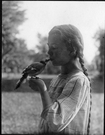 Little girl kissing pet bird, ca. 1912 embrasse moi
