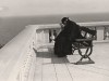 un homme d'église presbyte assis sur un banc sur une terrasse surplombant la mer