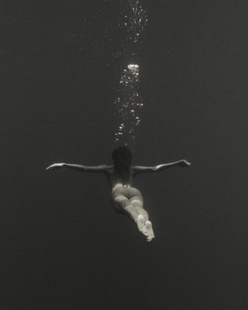 une femme nue, les bras en croix, semble voler sous les eaux