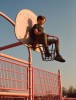 un jeune garçon assis sur le panier d'un panneau de basket