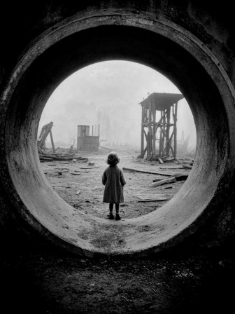 une petite fille debout dans une grande canalisation en béton armé pour système de drainage évoquant les génériques de James Bond