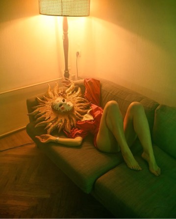 sous le lampadaire du salon, allongée sur le dos sur la banquette, une femme portant un masque de soleil