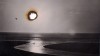 le soleil comme un trou de brûlure de cigarette dans une photo de bord de mer