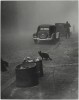 une rue déserte dans la brume, les poubelles sorties sur le trottoir, une traction avant garée, un homme s'éloigne, la ville est livrée au chat