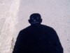 l'ombre d'un homme sur le trottoir, la tête calée sur le dessin à la craie d'un visage