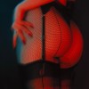 la lumière rouge des néons sur une femme en porte-jarretelles, aux fesses résillées